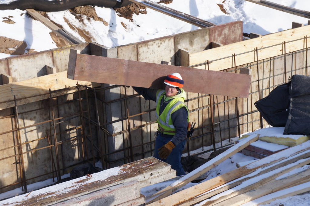 construction site worker carrying plank